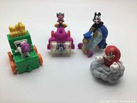 Three vintage Warner Bros Animaniacs character rolling toys on wheels showing colorful figures perched on small wheeled bases