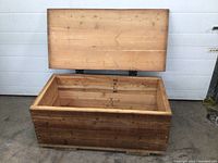 Open view of the solid wood storage chest, showing interior and lid with metal hinges.