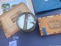 Various collectibles including vintage paper ephemera, Old Briar tin, blue United Nations first day cover book, and El Rojan wooden cigar box.