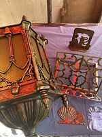 Photo of the gothic style hanging light showing its metal frame and the brass book stand, key hook, and bookend placed nearby.