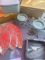 Photo showing some jewelry boxes and a red leaf-shaped metal tray and the metal candle holder with leaf details