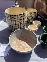 Large cream ceramic planter with black geometric pattern, medium matching planter, large light gray decorative bowl, and small white planters shown.