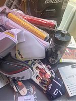Box containing various sporting items including gloves, water bottle, and rolled colorful posters.