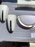 Two tapered glass shade sconces with chrome accents, and one half-moon shaped frosted glass sconce on fabric background