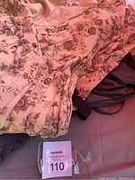 Floral print dress with beige/light background and brown floral design shown folded to highlight fabric and pattern