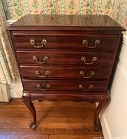 Front view of wooden Crescent dresser with four drawers and brass handles, showing polished dark wood finish and minor scratches.