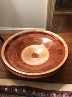 Front-facing photo showing the bowl's interior pattern with light wood center and reddish-brown wood body, polished finish.