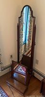 Full length wooden swivel mirror with scalloped top edge and finial details.
