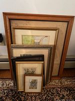 Photo of six framed artworks stacked with different frame styles and sizes.