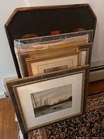 Multiple framed artworks stacked upright, including some wrapped in bubble wrap.