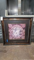 Full view of framed wall art showing square frame with dark wood tone and detailed vintage map print in pink and purple hues.