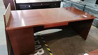 Front view of main executive desk with drawers and laminate surface showing some scratches.