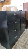 Two black metal filing cabinets by HON showing front and side views with scratches and wear.