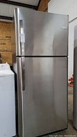 Front view of stainless steel top-freezer refrigerator with closed doors.