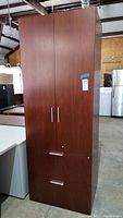 Front view of the closed laminate storage tower showing wood grain finish with two doors and two file cabinet drawers at the bottom
