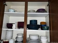 Cupboards filled with a variety of ceramic and glass plates and bowls in various colors and sizes.