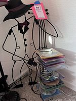 Metal wireframe musician CD storage stand shaped like a musician playing a string instrument, holding stacked CDs.