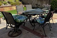 Photo showing full patio set including table, six chairs with cushions, and umbrella folded in the center of the table.