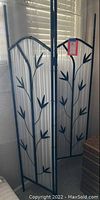 Full view of the three-panel metal room screen with white fabric and bamboo leaf decorations.