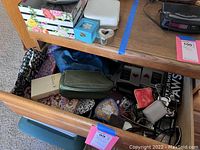 Top view showing a wooden dresser drawer and top surface filled with trinket boxes, sunglasses, small pouches and bowls in assorted colors and designs
