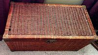 Top view of rectangular wicker chest closed showing woven wicker and damage on the lid