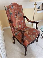 Full view of upholstered armchair showing carved arms and patterned fabric