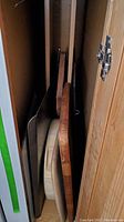 Photo showing multiple baking sheets and wooden cutting boards stacked vertically in cabinet