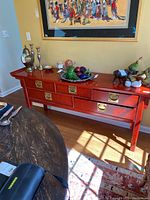 Front view of red-toned credenza with decorative items on top