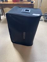 Black zippered carrying case for foldable bed with carrying handle visible on top.
