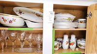 Top cabinet shelf with large serving bowls, oval platters and assorted fruit-pattern pieces