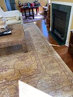 Full view of the rug running alongside a fireplace, showing its cream base and floral oriental design.