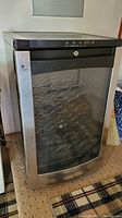 Front view of GE Profile wine chiller refrigerator showing glass door, control panel, and internal metal racks for wine bottles.