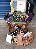 Wide view showing about 20 used art books arranged on and around a small wooden table, various titles and covers visible.