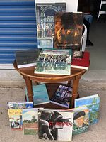Photo showing a collection of art books arranged on and around a small wooden round table, titles include David Milne Watercolours, Rembrandt and the Bible, St. Peters, Impressionism, Van Gogh, and others.