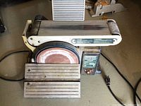 Front view showing belt sander on top and disc sander on the side with work tables attached