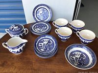 Full view of all items arranged on table including plates, bowls, cups, sugar bowl with lid and creamer jug