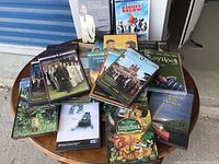 Multiple DVDs including Downton Abbey seasons and other movies arranged on a round wooden table.