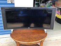 Front view of HP curved monitor mounted on wooden table, showing screen and logo
