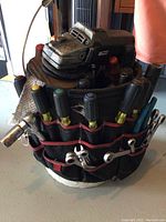 Side view of Husky tool belt filled with various screwdrivers and wrenches around a white bucket. Angle grinder with disc visible on top.