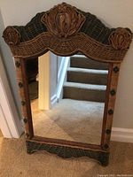 Full view of the wicker/rattan framed rectangular mirror positioned against a wall near stairs.