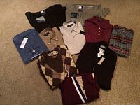 Overview of all clothing items laid out including pants, button-down shirts, polo shirt, sweater vest, and plaid shirt.