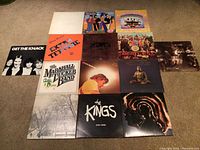 Photo shows all 15 vinyl record album covers laid out together on carpet. Albums include The Beatles, George Harrison, Steve Miller Band, The Marshall Tucker Band, Cat Stevens, The Kings, Get The Knack.