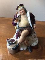Front view of Old King Cole figurine seated with pipe and cup in hand