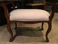 Front view showing curved wooden legs, carved apron, and cushioned white seat upholstery.