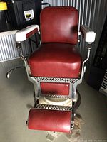 Full front view of chair showing red vinyl upholstery, white armrests, chrome frame and footrest.
