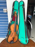 Full view of violin in open case showing violin, bow, and case interior