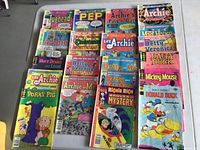 Group photo of 20 vintage comic books including Archie and Disney titles laid out on a flat surface showing colorful covers with some visible wear and pen marks.