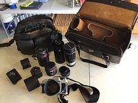 Overview of lot on tabletop showing camera bag, various lenses, camera body and accessories