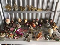 Wide view of assorted vintage Christmas ornaments arranged on a white grate shelf.