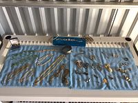 Full display of all costume jewelry items on blue towels including necklaces, bracelets, brooches, earrings, and rings, showing condition and pairing.